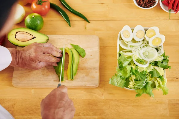 Mãos Homem Sênior Cortando Abacate Fazer Salada Saudável Para Jantar — Fotografia de Stock