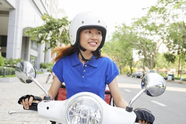 笑年轻的亚洲送货妇女骑摩托车 赶忙送火辣的食物给顾客 — 图库照片