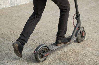 Elektrikli scooter kullanan genç bir adamın kesilmiş görüntüsü.