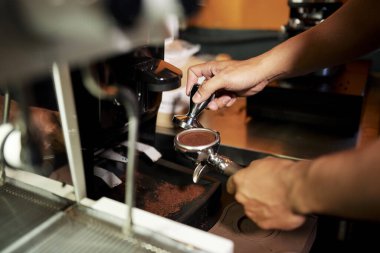 Kahve makinesiyle demlenmeden önce barista kahve makinesini tutuyor ve espresso duble spout portafilter ile Arabica zeminini dolduruyor.