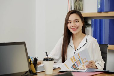 Güzel gülümseyen kadın proje yöneticisinin portresi web sitesi arayüzü örneğiyle belgeyi kontrol ediyor