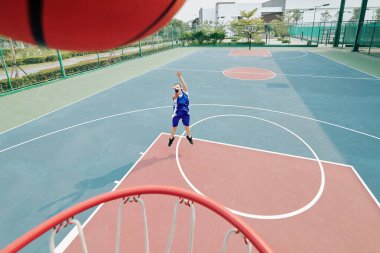 Profesyonel bayan basketbolcu dışarıda oynarken topu potaya atıyor.