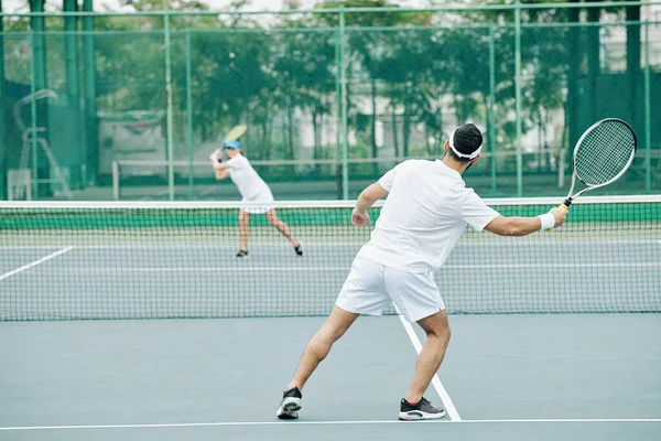 白の制服を着たカップルがテニスコートで試合をする — ストック写真
