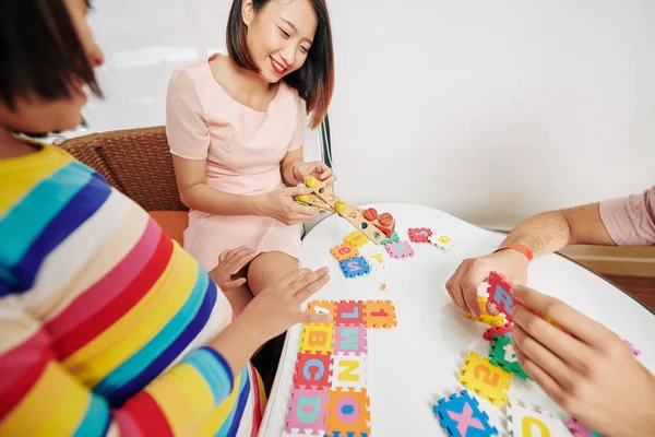 Rodzice Pokazując Ciekawską Małą Córkę Alfabetu Puzzle Logiczne Zabawki — Zdjęcie stockowe