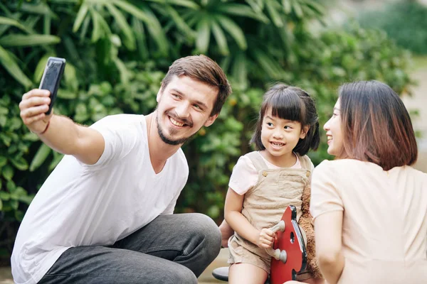 陽気な若いです白人男取ります自画自慰行為で彼の可愛いですベトナムの妻と娘で遊び場 — ストック写真