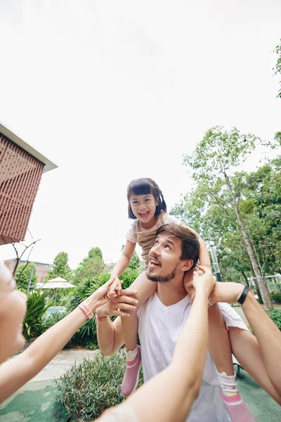 彼らは公園で週末を過ごすとき幸せな若い父親は彼の小さな娘にピギーバックライドを与えます — ストック写真