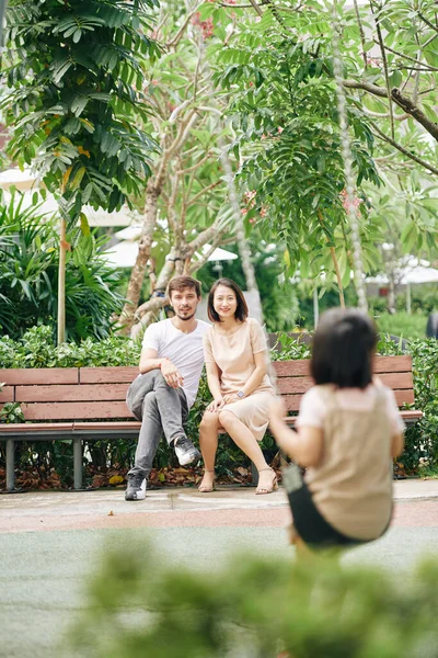 Ευτυχισμένοι Νέοι Πολυεθνικοί Γονείς Κάθονται Στον Πάγκο Και Κοιτάζουν Την — Φωτογραφία Αρχείου