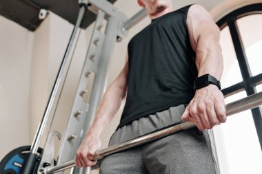 Formda kaslı bir adam spor salonunda ağırlık kaldırma egzersizleri yapıyor.