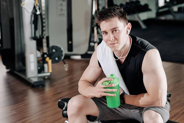 英俊潇洒的笑脸运动员在健身房锻炼后喝水的画像 — 图库照片