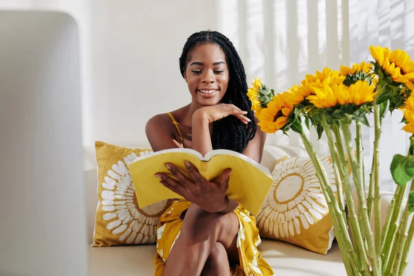 Hermosa Joven Negra Sentada Sofá Leyendo Libro Interesante —  Fotos de Stock