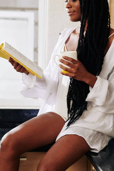 Hermosa Joven Negra Pijama Lino Bebiendo Café Mañana Leyendo Libro —  Fotos de Stock