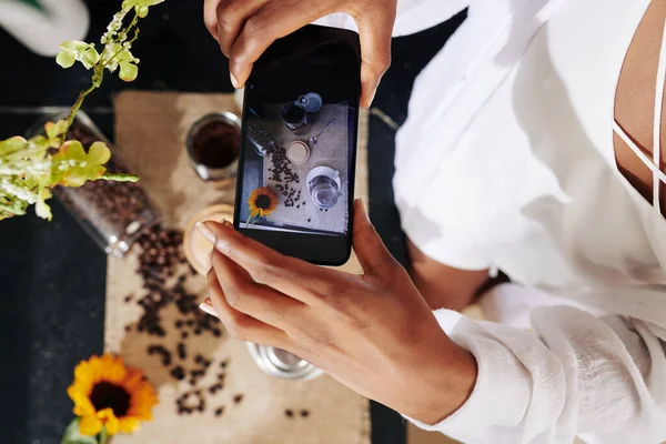 年轻女子为社交媒体拍摄咖啡壶 豆子和花朵的平铺照片 — 图库照片