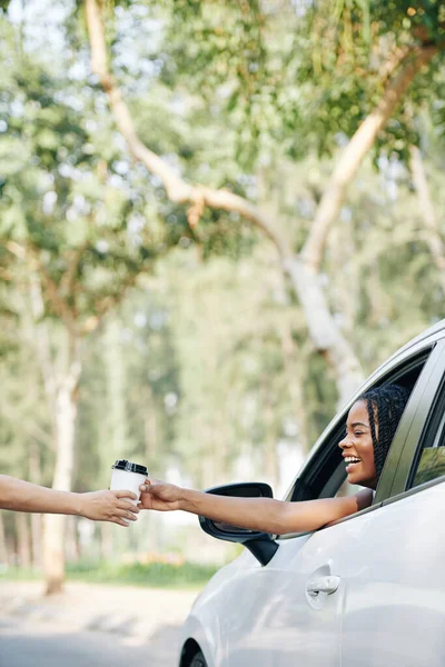 Excited happy young Black woman buying take out coffee in drive through cafe