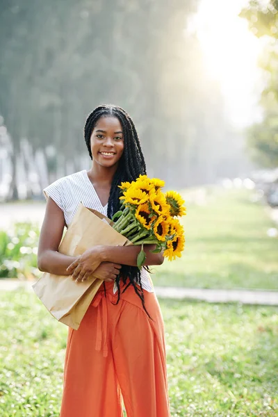 美丽的年轻黑人妇女站在室外 束着向日葵的画像 — 图库照片