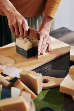 Keskin bıçakla iki renkli sabun kesen kadının elleri.