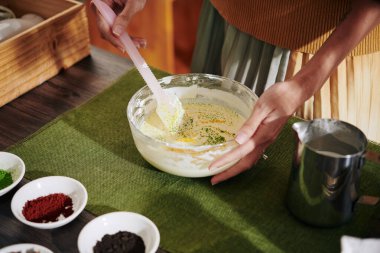 Erimiş sabunu toz renkleriyle karıştırırken plastik spatula kullanan bir kadının yakın plan görüntüsü