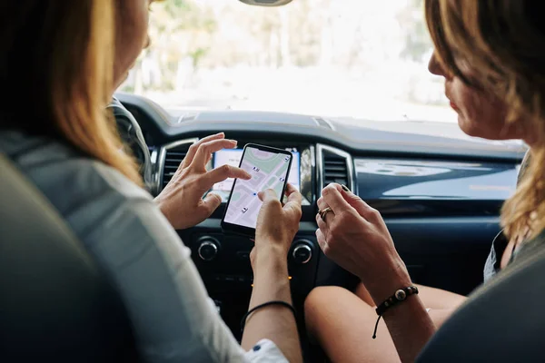 年轻女性坐在车里 看着智能手机屏幕上的地图 讨论如何更好地到达目的地 — 图库照片