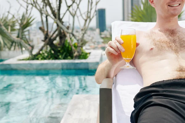 笑顔若いです男に横たわっていますChaise Loungeと冷たいフルーツカクテルを飲みます — ストック写真