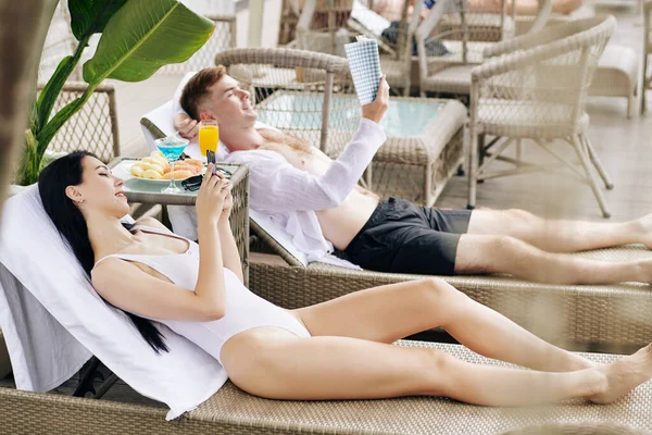 Beautiful Happy Young Couple Resting Chaise Lounges Swimming Pool Reading — Stock Photo, Image