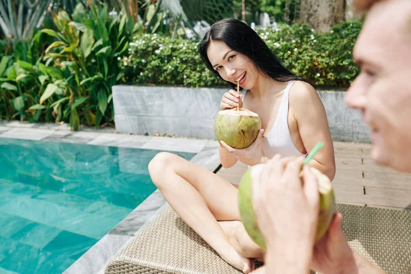 Mujer Joven Sonriente Bebiendo Cóctel Coco Mirando Cámara Cuando Sienta — Foto de Stock