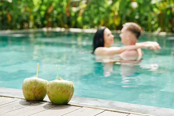 Jong Paar Liefde Zoenen Zwembad Twee Verfrissende Kokosnoot Cocktails Voorgrond — Stockfoto