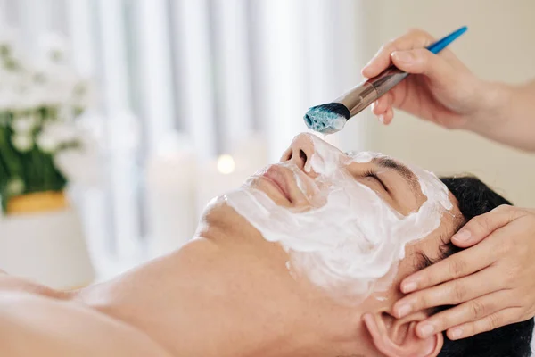 美容师在男性患者的面部应用年轻化面罩 — 图库照片