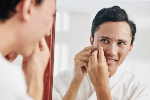 Sorrindo Mestiço Homem Olhando Para Espelho Espremendo Espinhas — Fotografia de Stock