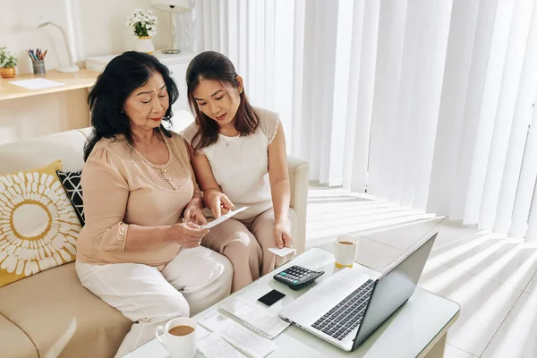 나이든 어머니가 컴퓨터를 온라인 요금을 수있도록 아시아 — 스톡 사진