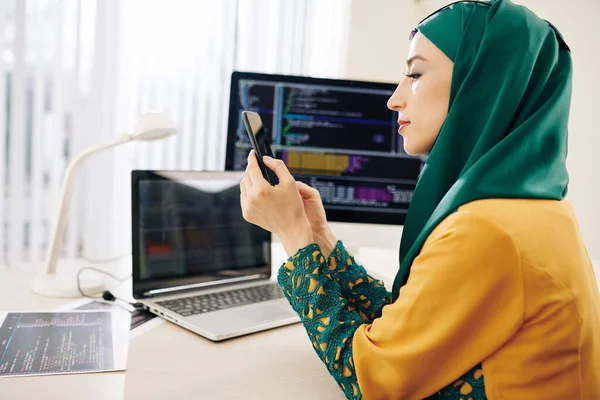 Pensive Fiatal Muszlim Szoftverfejlesztő Asztalnál Ellenőrzi Szöveges Üzeneteket Okostelefon — Stock Fotó