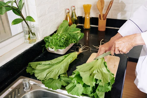 Detailní Záběr Muže Odřezávajícího Kořeny Salátu Při Vaření Salátu Doma — Stock fotografie