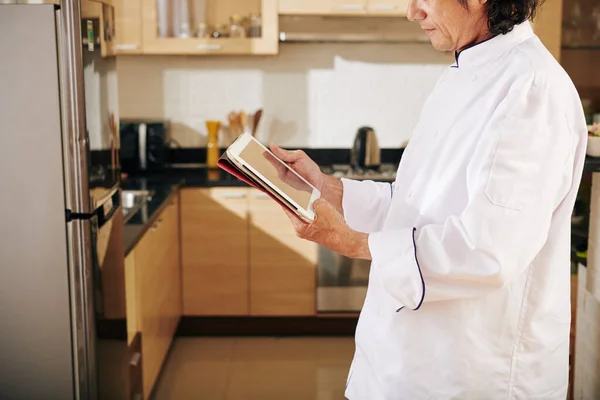 厨师站在家里厨房和平板电脑阅读菜谱的剪影 — 图库照片