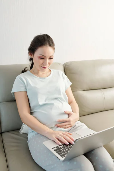 Ung Gravid Asiatisk Kvinna Bekväm Pyjamas Sitter Soffan Hemma Tittar — Stockfoto