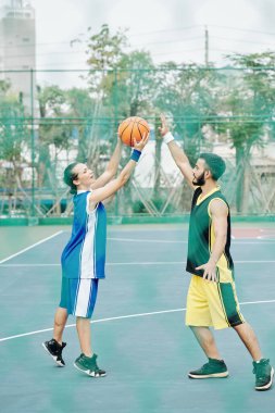 Sokak basketbol sahasında basketbol oynayan çok ırklı gençler