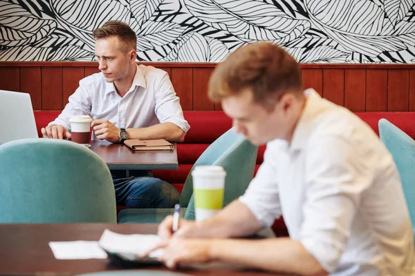 Serio Joven Freelancer Con Taza Café Sentado Mesa Cafetería Artículo — Foto de Stock