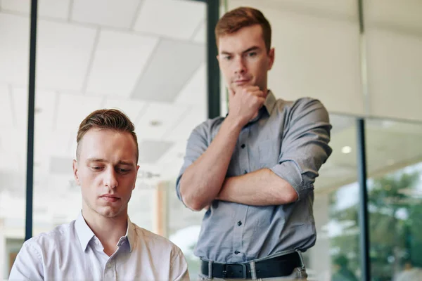 Joven Serio Escribiendo Términos Contrato Colega Pie Detrás Mirando Pantalla — Foto de Stock