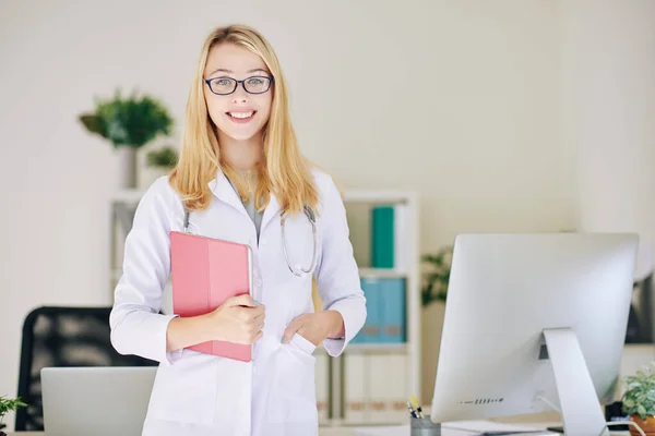 快乐的女全科医生 漂亮的面带微笑站在她的办公桌前 拿着平板电脑 — 图库照片