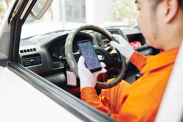 Varış noktasına gitmeden önce mobil uygulama üzerinden haritayı kontrol eden servis çalışanı