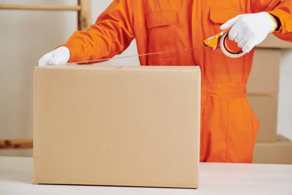 Üniformalı Bir Servis Çalışanı Karton Kutuyu Yapışkan Bantla Mühürlüyor — Stok fotoğraf