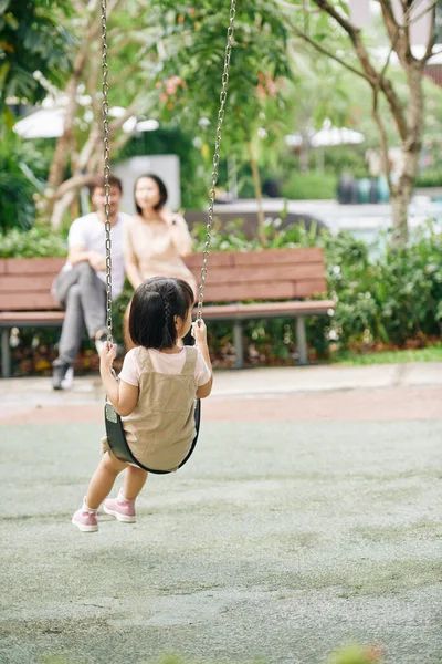 Niña Balanceándose Cuando Sus Padres Descansan Banco Parque —  Fotos de Stock