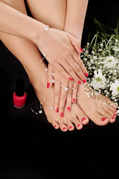 Woman posing with fresh manicure and pedicure and holding pearl strip after visiting beauty salon