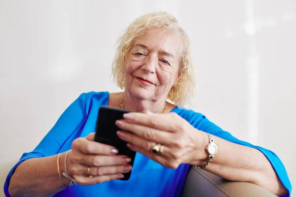 Lächelnde Seniorin Liest Sms Von Enkeln Auf Smartphone — Stockfoto