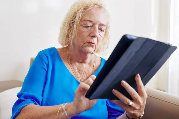 タブレットコンピュータ上でオンラインニュースを読んで深刻な高齢女性 — ストック写真