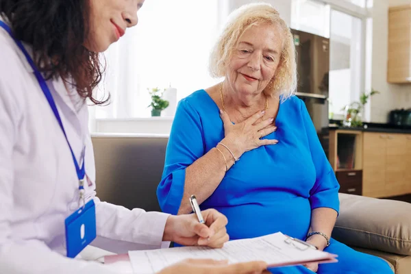 Läkare Besöker Äldre Kvinna Hemma Och Skriver Ner Sina Klagomål — Stockfoto