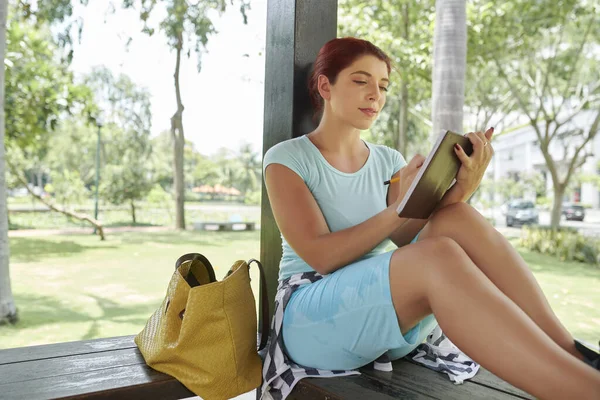 庭の家に座って感謝日記にメモを取る美しい若い女性 — ストック写真