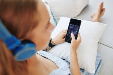 Akıllı telefon uygulaması üzerinden kulaklıktaki sesi ayarlayan kadının yakın plan görüntüsü