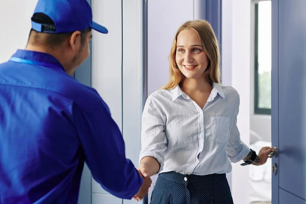 Lächelnde Schöne Junge Frau Öffnet Eingangstür Und Grüßt Reparaturarbeiter — Stockfoto