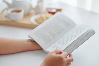 Genç bir kadının sabah kahvaltısını ve kitap okumasını yakından çek.