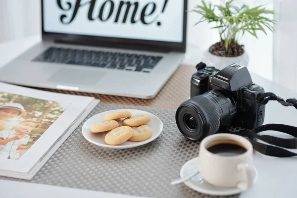おいしい自家製のクッキーとプレート ロックダウン中に自宅から働く写真家のテーブルの上に印刷された写真とコーヒーとアルバムのカップ — ストック写真