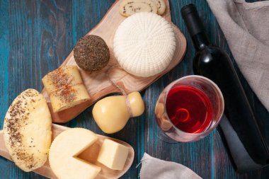 Peynir seti. Halumi, Caciotta, Caciocavallo, peynir çubukları, Suluguni, Belper knolle, Provencal otlu peynirli rulo. Tahta ve gri keten kumaş üzerinde. Yukarıdan görüntüle.