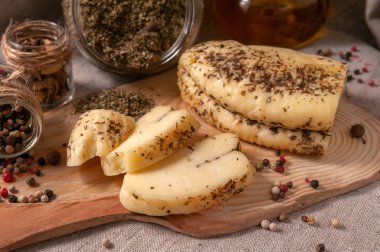 Peynir seti: halumi, caciotta, caciocavallo, peynir çubukları, suluguni, belper knolle, provencal otlarla peynirli rulo. Tahta ve gri keten kumaş üzerinde. Yukarıdan görüntüle.